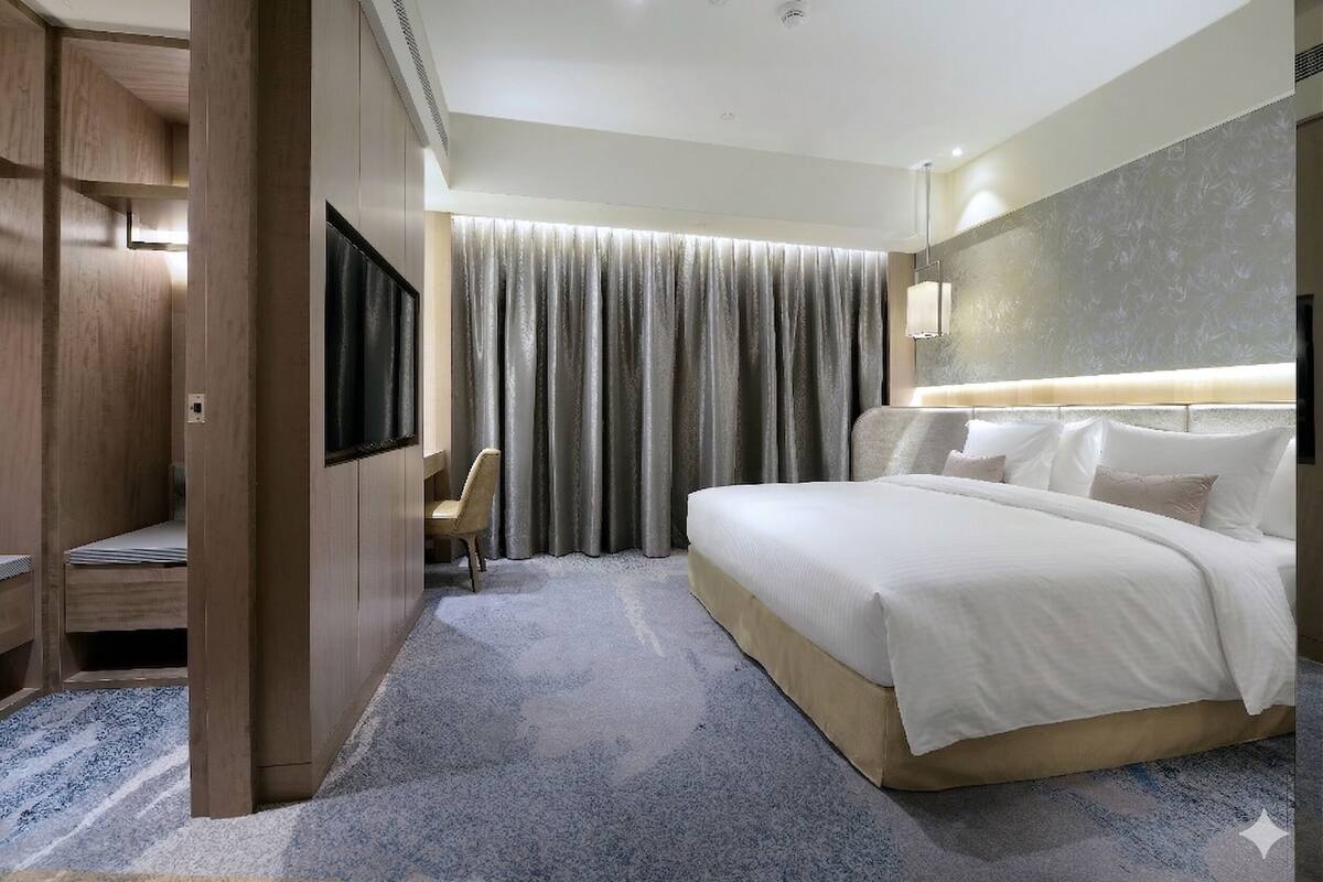 Quarto de hotel com cama grande, mesa de trabalho com cadeira, televisão e cortina.