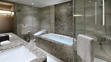 A modern bathroom with a glass-enclosed shower, a bathtub, and a vanity with a sink.