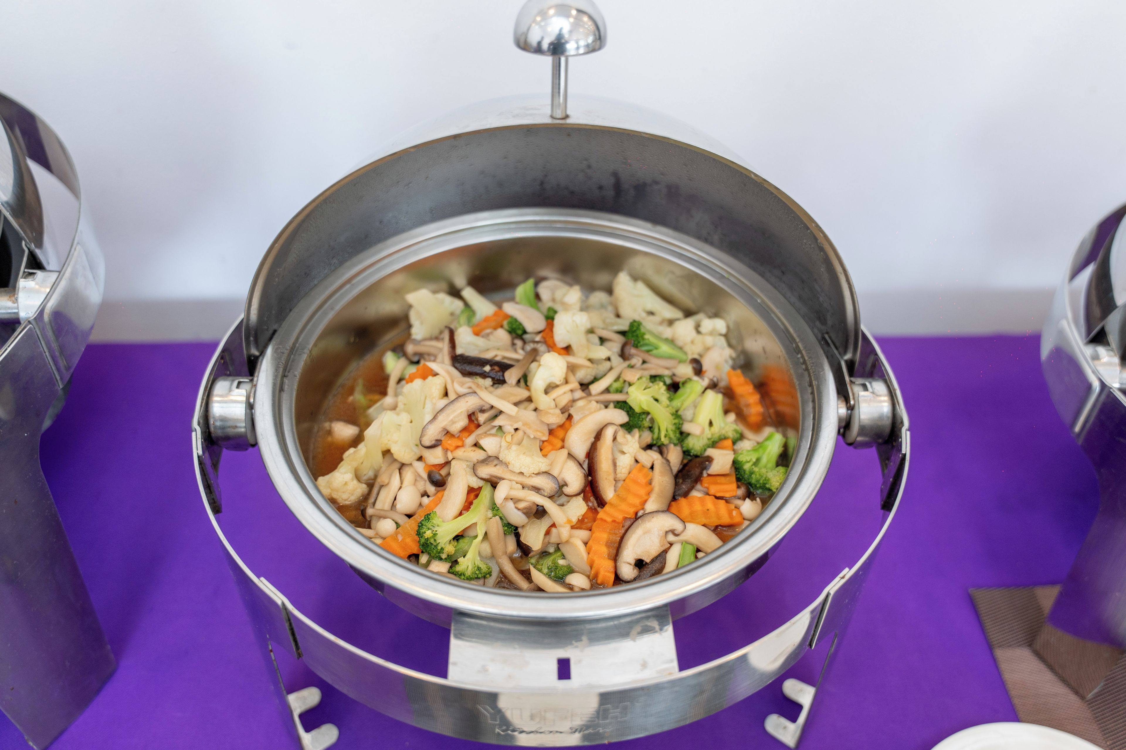 A stainless steel pot with a lid on a purple surface.