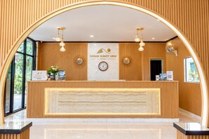 A reception desk at Savanh Sunset View Resort with a clock, decorative wall panels, and hanging lights. - Vang Vieng Savanh Sunset view resort (Vang Vieng)