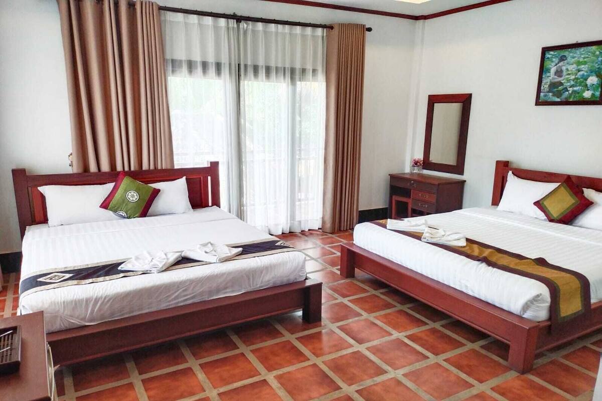 Camera d'albergo con due letti, una testiera in legno, un comodino, uno specchio e un quadro appeso al muro.