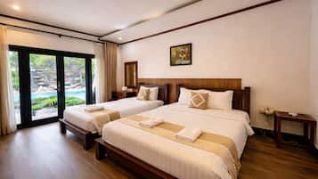 A hotel room with two beds, a large window with curtains, a wooden floor, and a painting on the wall.