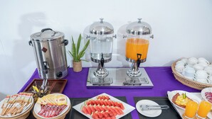 Montaje de un bufé de desayuno con máquinas de café, dispensadores de jugo y una variedad de alimentos.