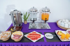 Un'area colazione a buffet con macchine da caffè, distributori di succo e diversi tipi di cibo.