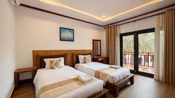 A hotel room with two beds, a wooden headboard, a painting on the wall, and a balcony with curtains.