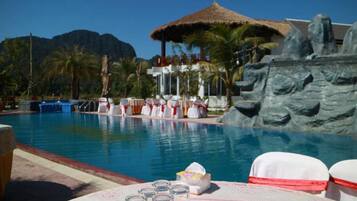 Relax by the serene pool surrounded by lush greenery and a natural gazebo.