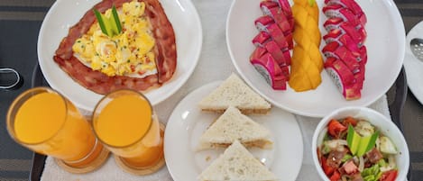A breakfast tray with scrambled eggs, bacon, toast, fruit, and a salad.