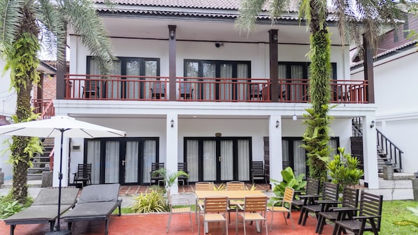 A two-story building with a balcony, outdoor seating area, and a staircase.