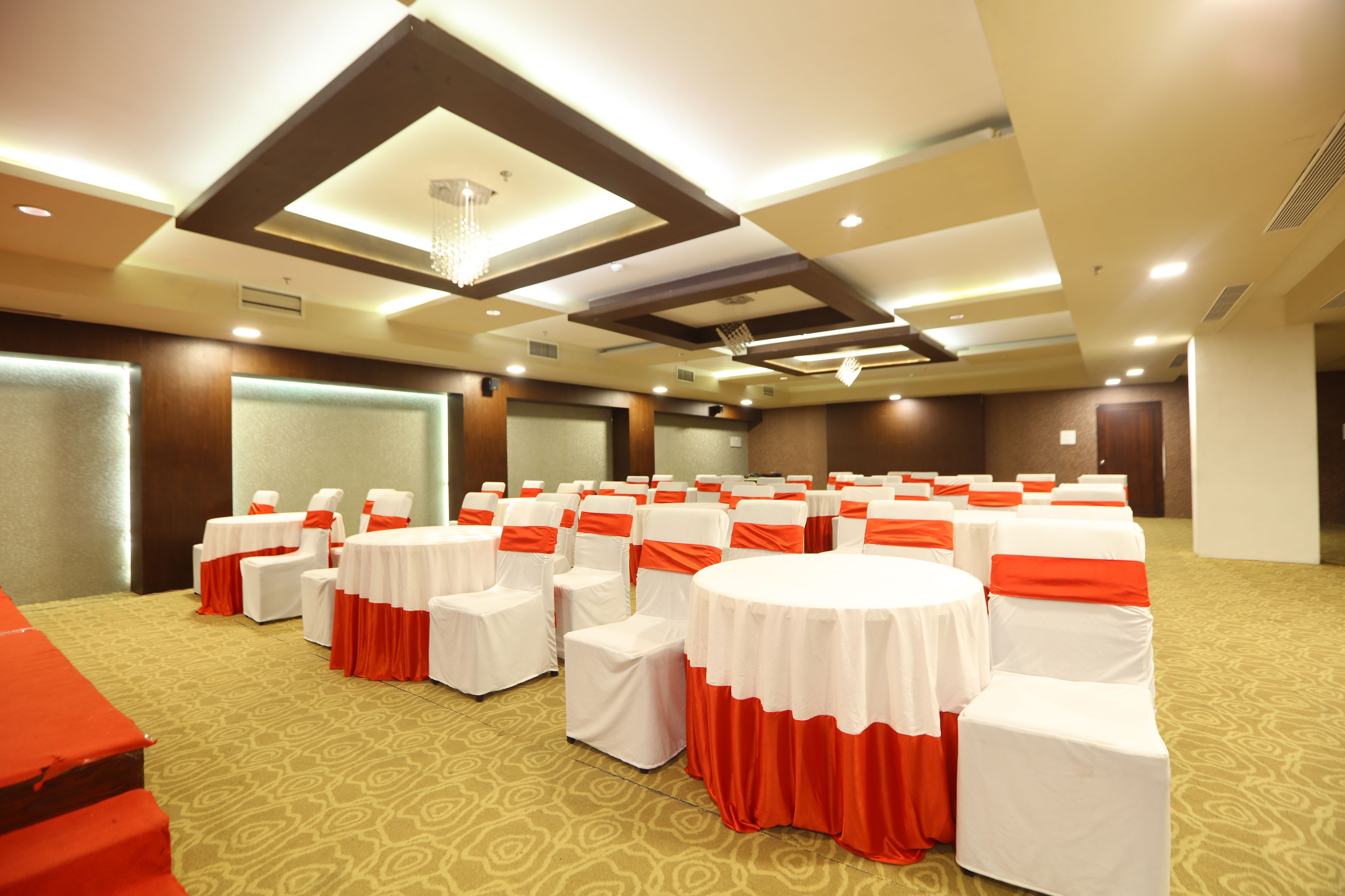 A conference room with rows of white chairs with red sashes, a large round table, and a carpeted floor.