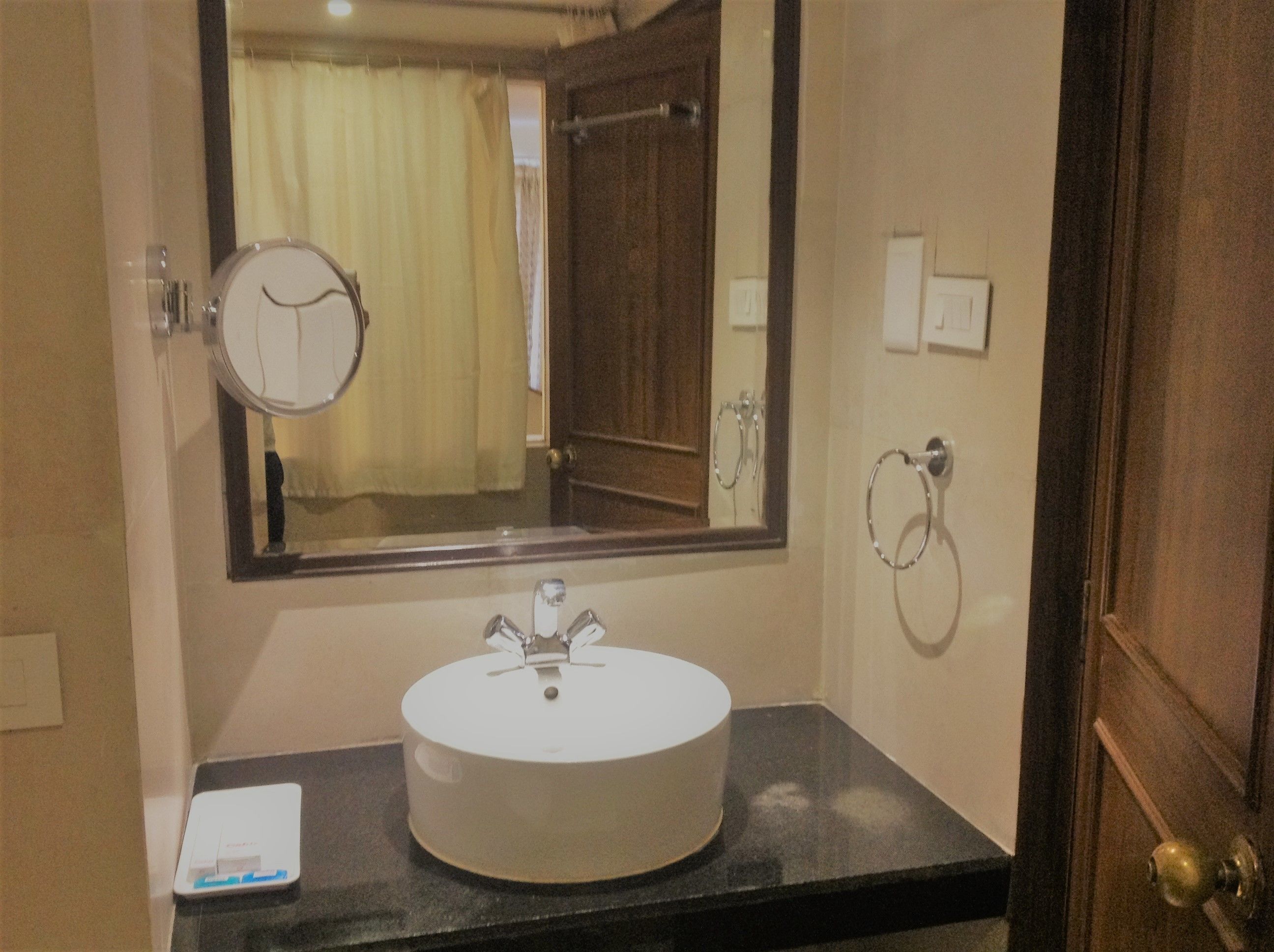 A bathroom with a round sink, a mirror, a towel rack, and a door.