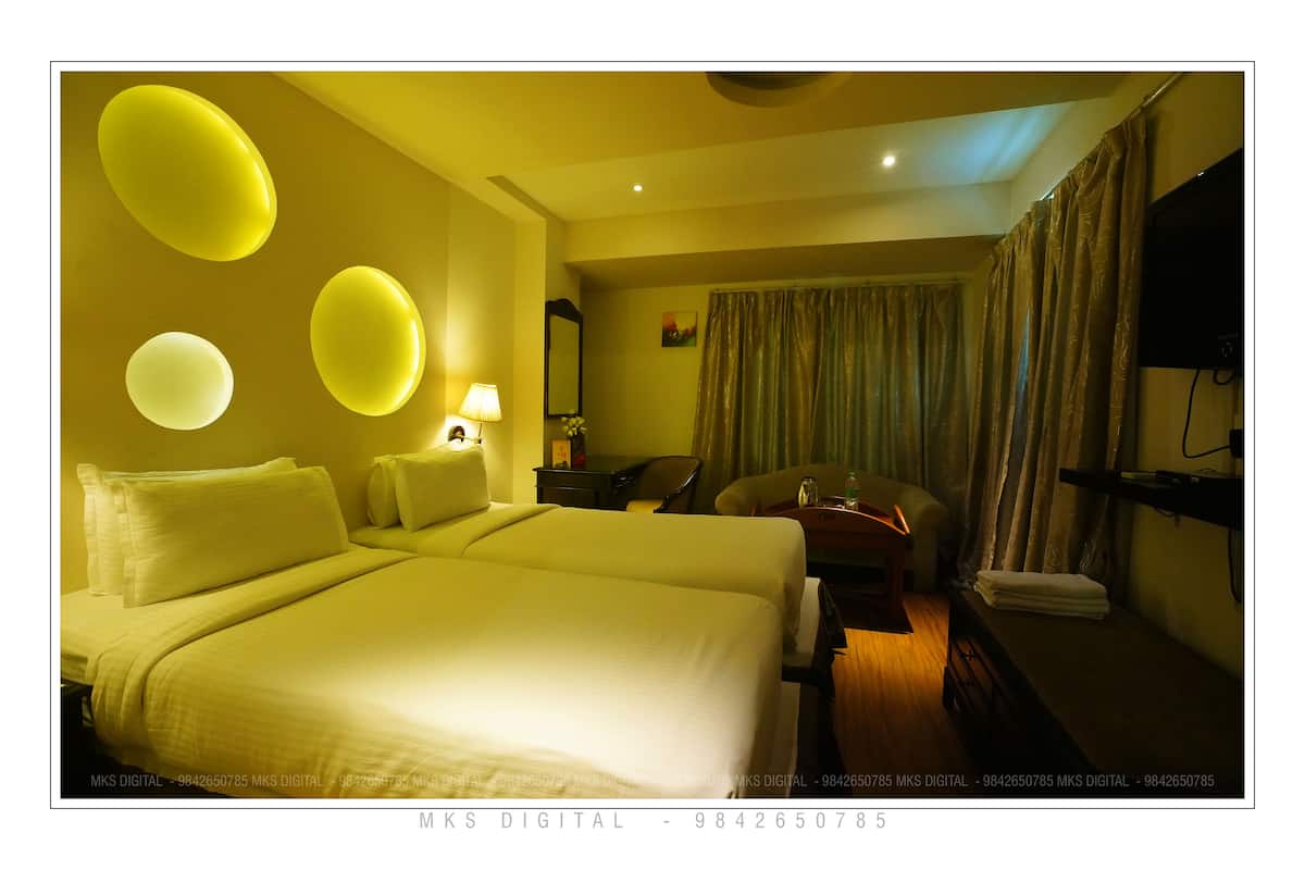 A hotel room with a large bed, a desk, a chair, a TV, and a curtain.