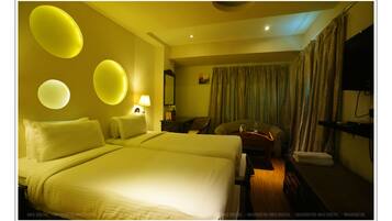 Une chambre d’hôtel avec un grand lit, un bureau, une chaise, une télévision et un rideau.