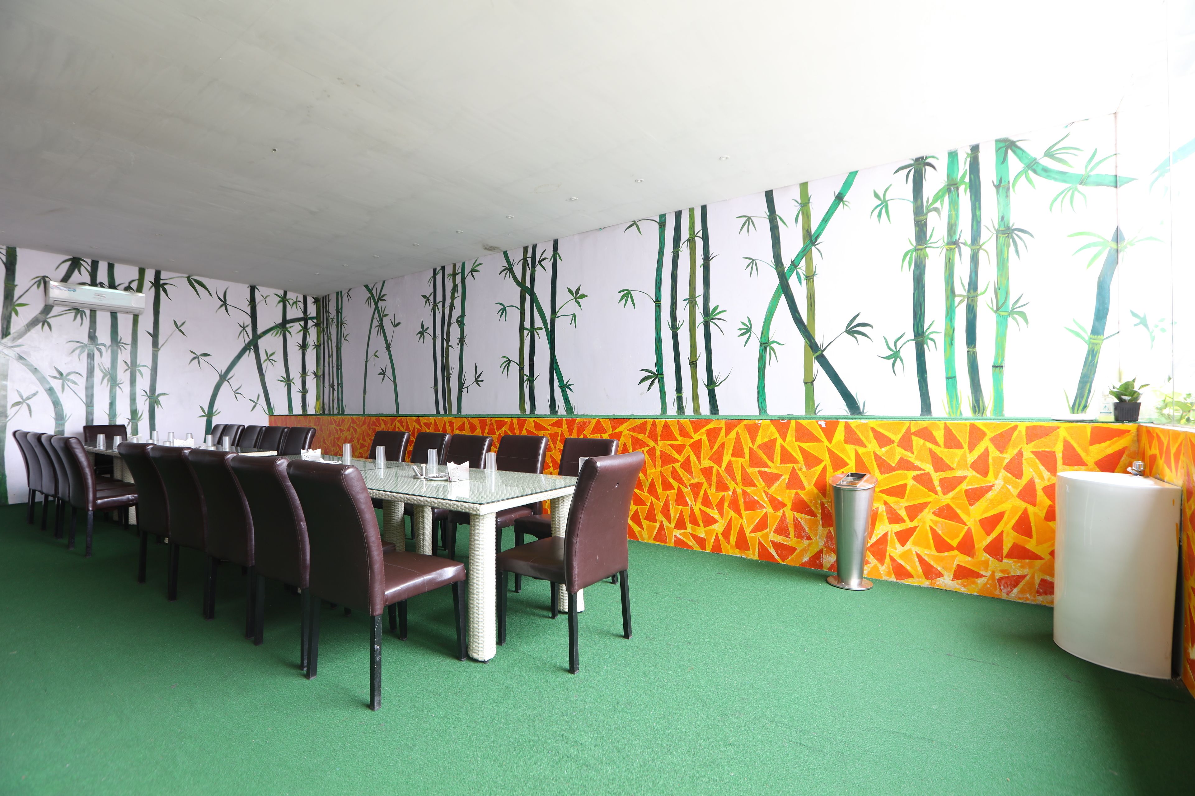 A dining area with a bamboo-themed wall, a green carpet, and a table set for six.