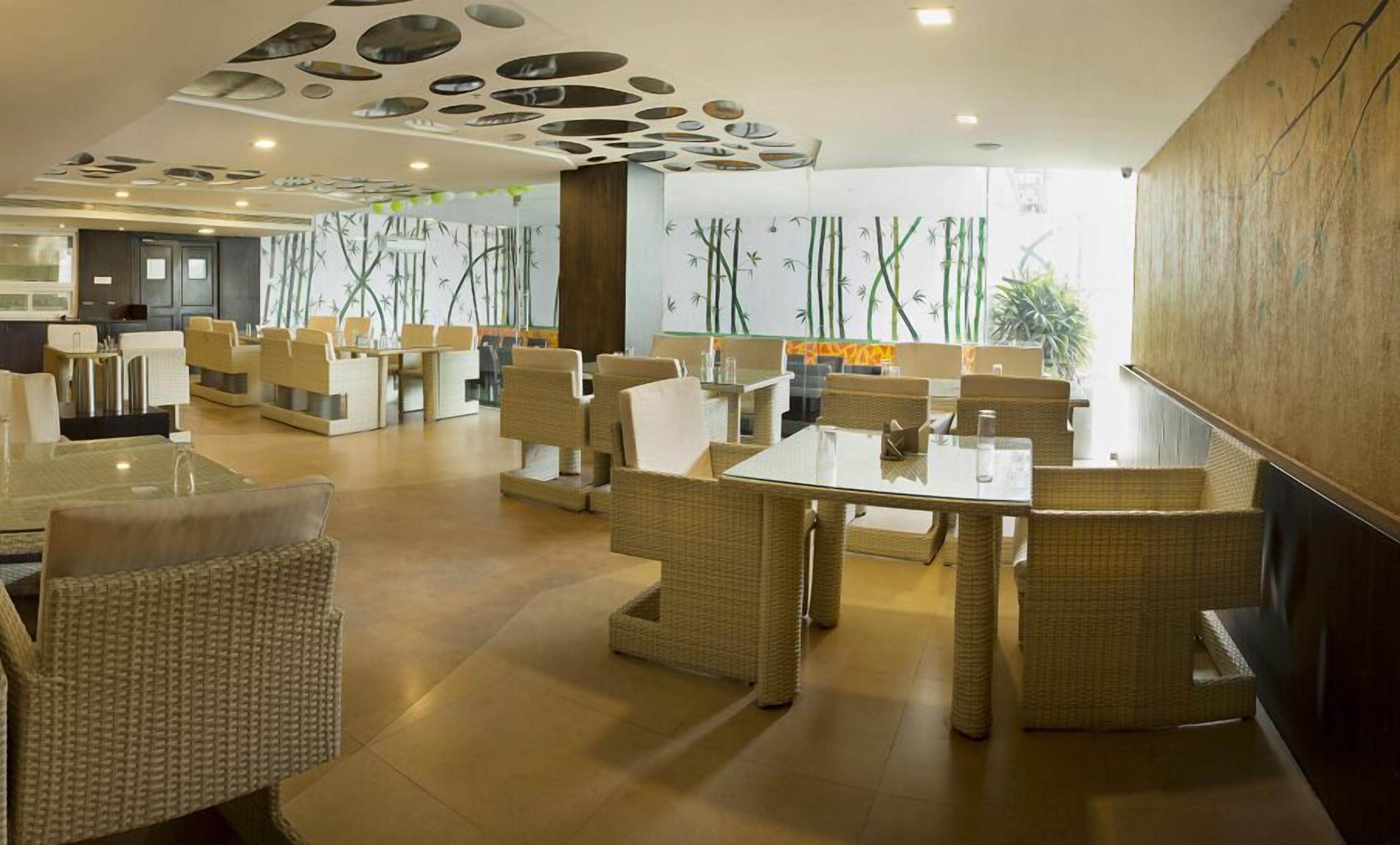 A modern restaurant with wicker furniture, a unique ceiling design, and bamboo wall art.