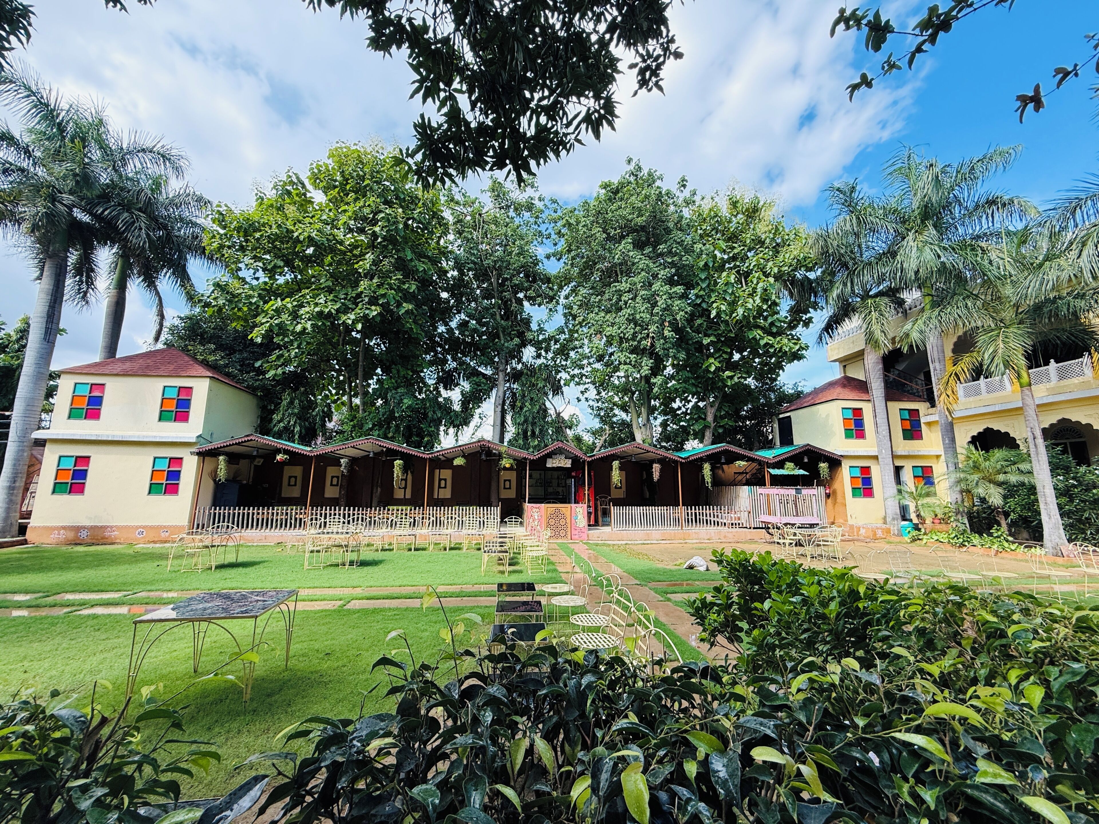 Un edificio de dos pisos con un jardín delantero, que cuenta con una cerca blanca y mobiliario exterior.