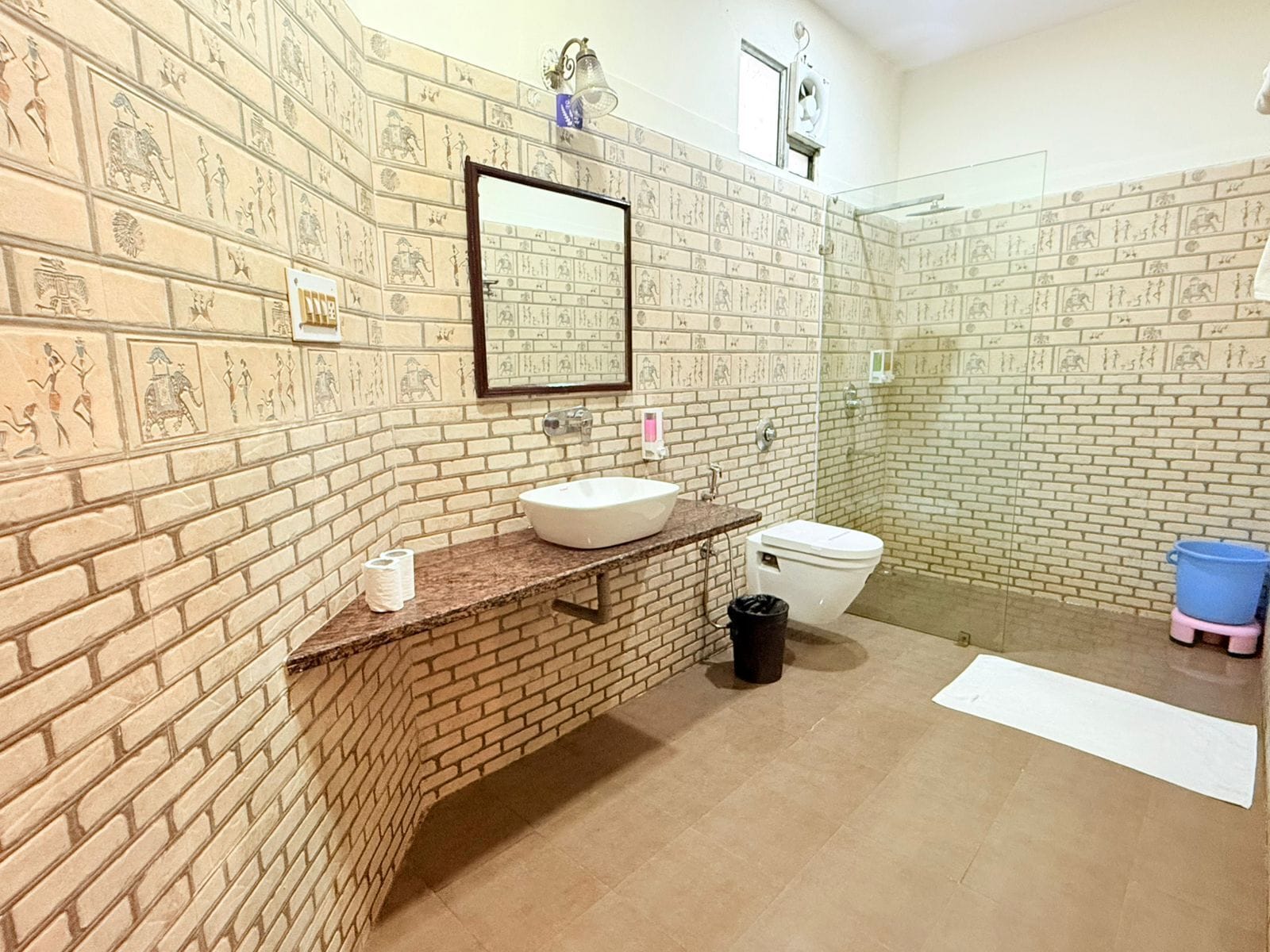 A bathroom with a brick wall, a sink, a toilet, and a shower area.
