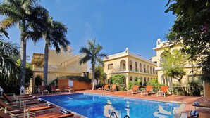 A pool area with lounge chairs and a clear blue pool. - Raj Palace Resort (Sawai Madhopur)