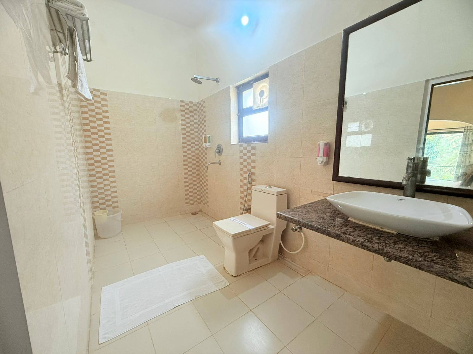 A bathroom with a shower, toilet, sink, and a large mirror.