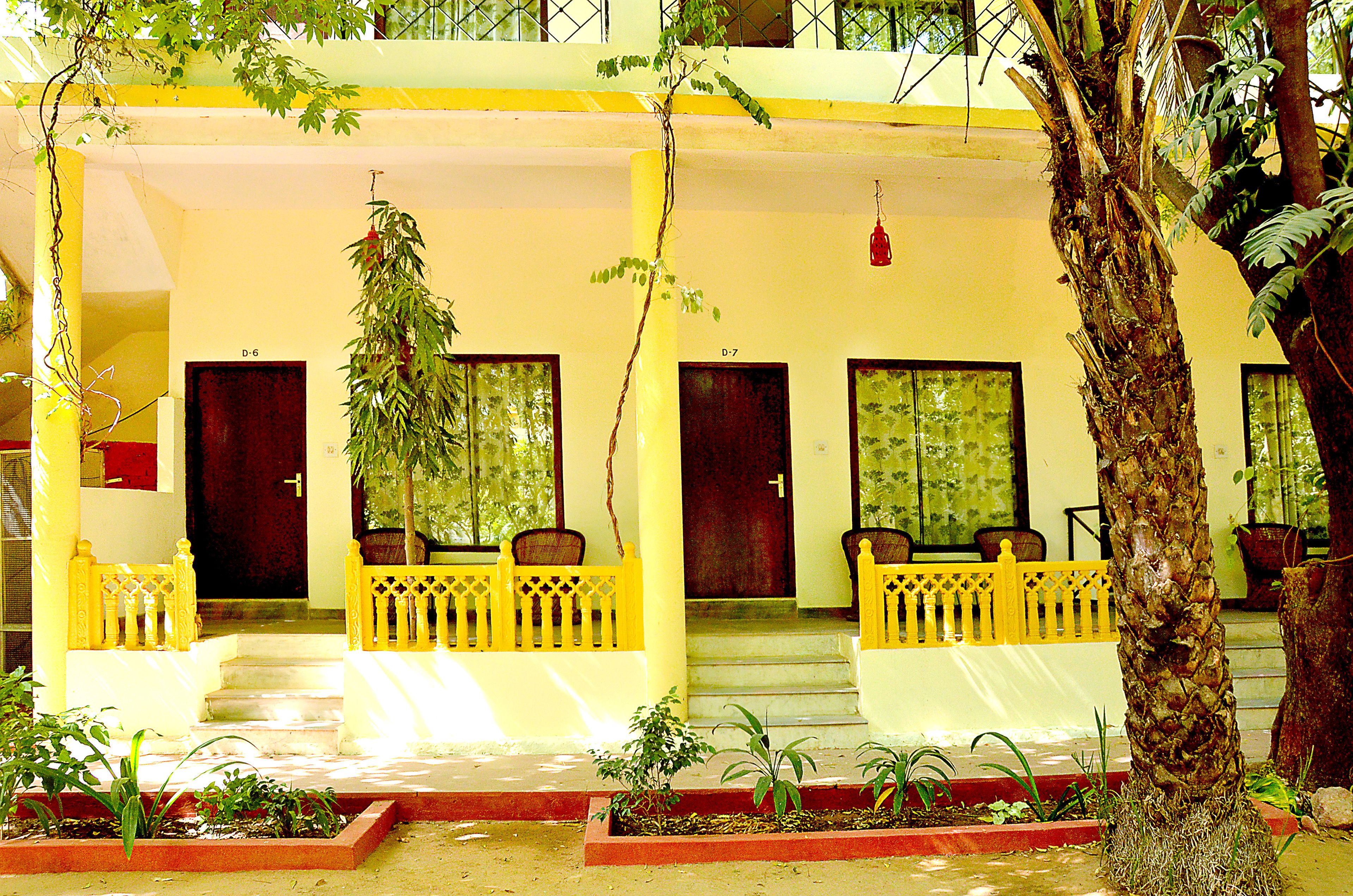 A two-story building with a yellow facade, multiple doors, and a staircase leading to the upper floor.