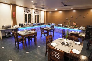 Un restaurante con zona de bar, mesas y sillas de madera y una barra iluminada en azul.