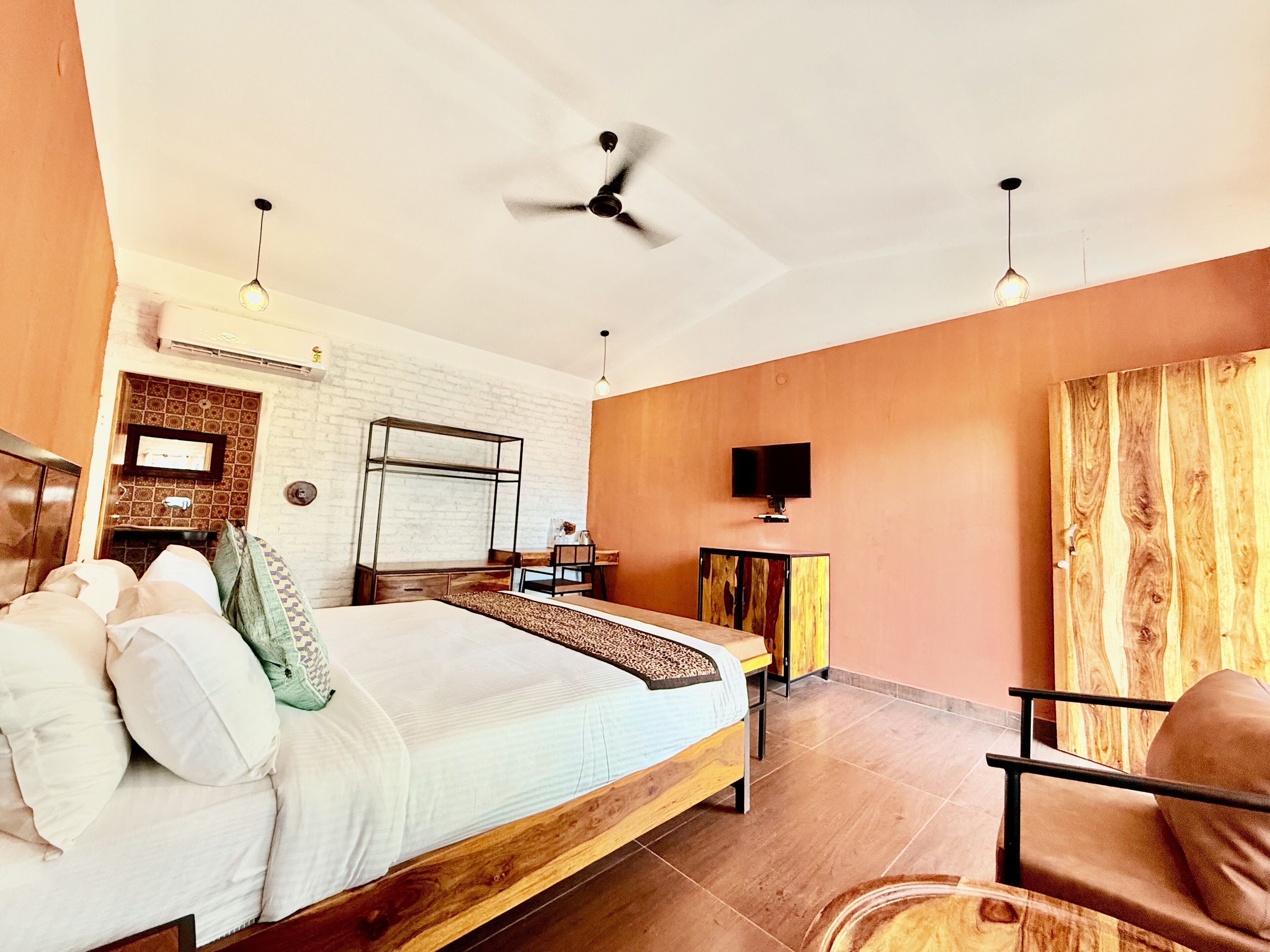 A bedroom with a bed, a desk, a chair, a television, and a ceiling fan.