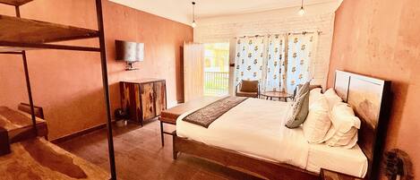 A bedroom with a bed, a TV, a ceiling fan, and a window with curtains.