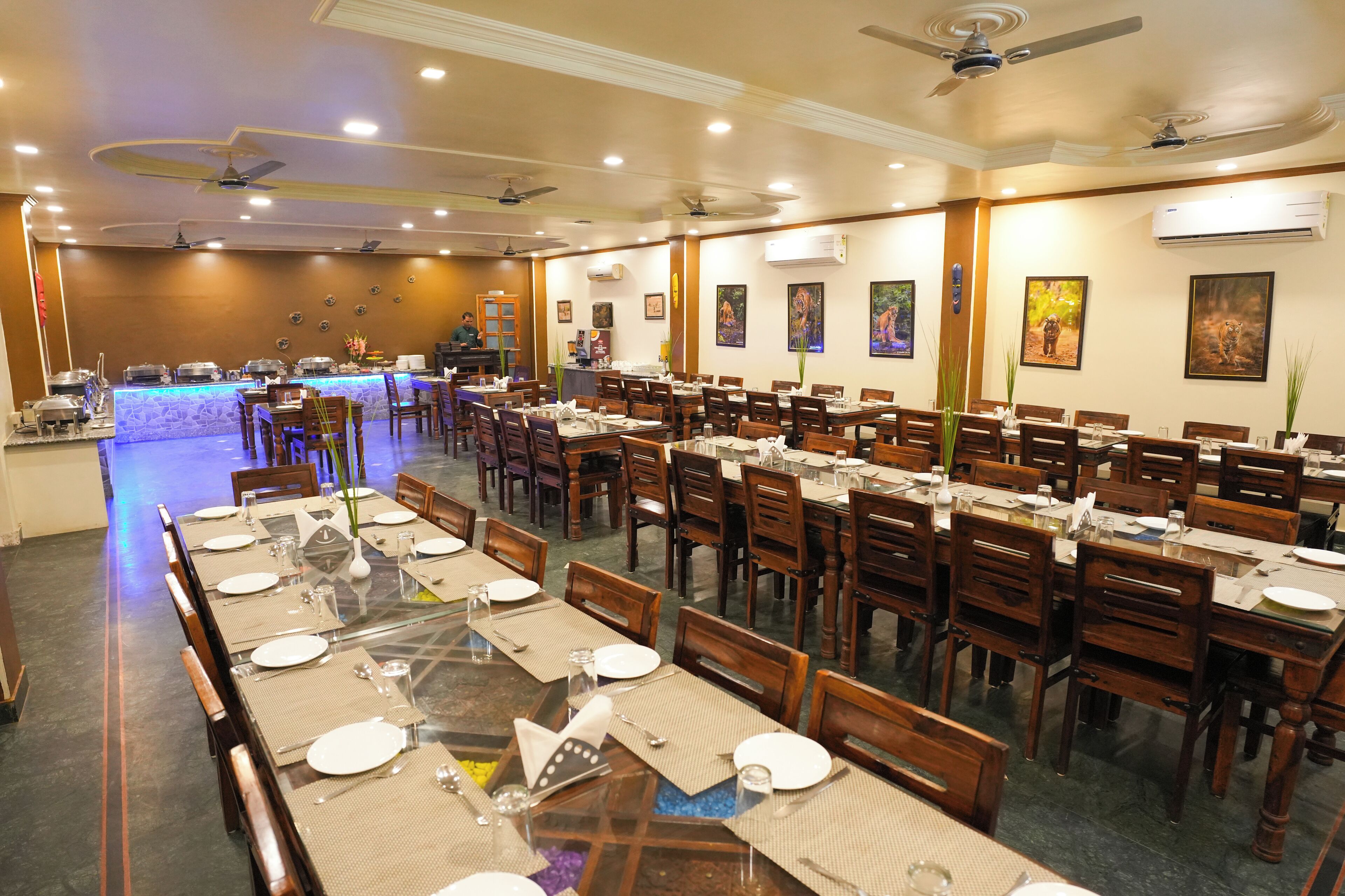 A spacious dining area with multiple tables and chairs, ceiling fans, and wall-mounted air conditioning units.