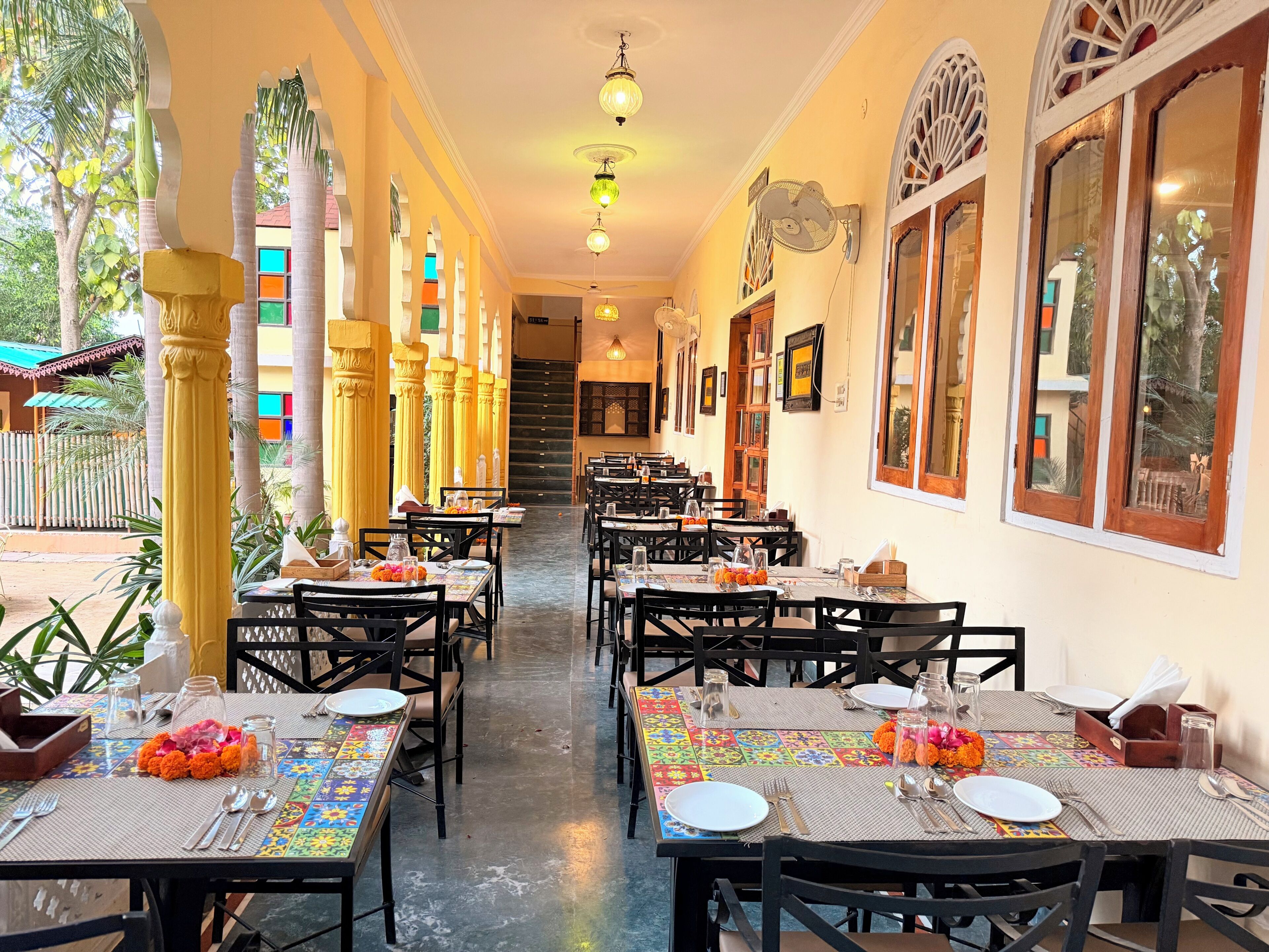 Un restaurant doté de nombreuses tables, de chaises et d’un escalier central.