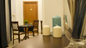 A dining area with a round table, two candles, and a vase with a candle holder. - B&B Dimora Cirillo (Naples)