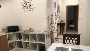 A room with a dining table, a microwave, and a shelf with kitchen items. - B&B Dimora Cirillo (Naples)