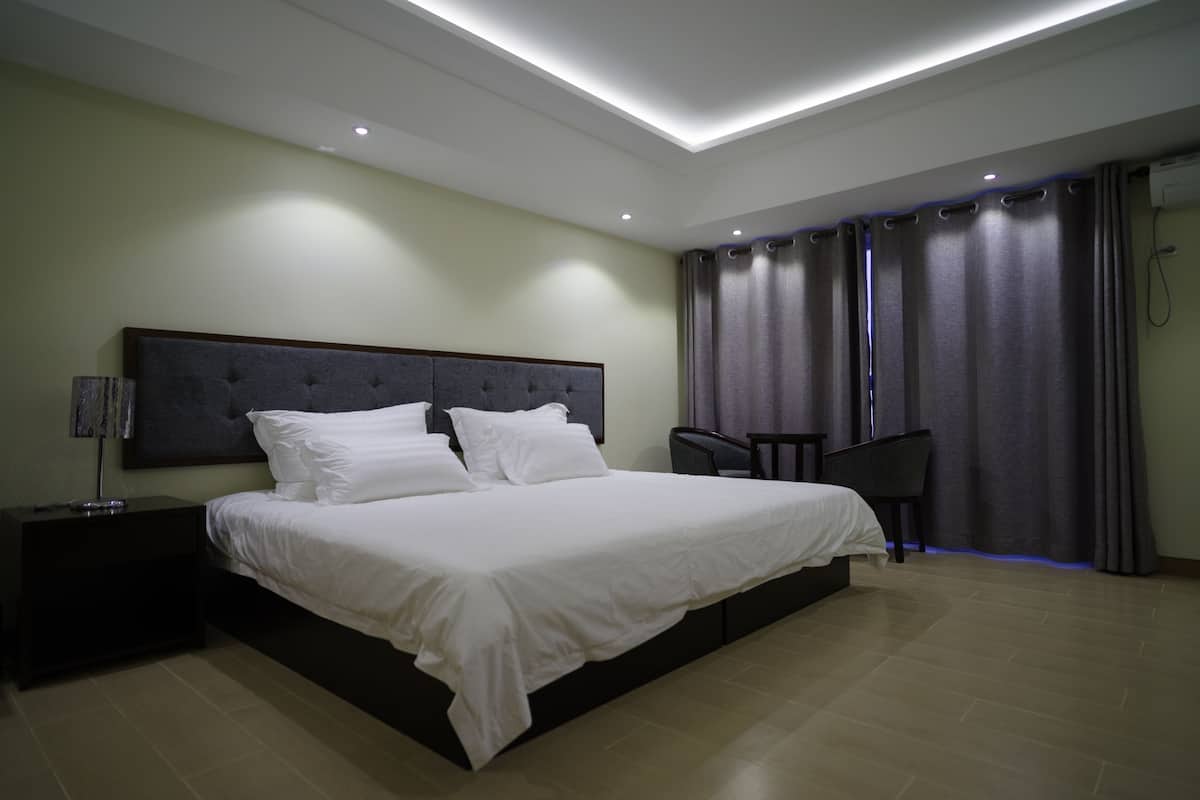 A modern bedroom with a large bed, a nightstand, a chair, and a desk.
