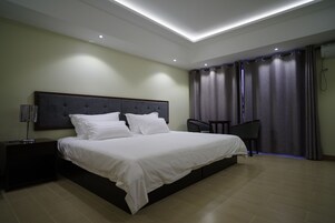 Un dormitorio moderno con una cama grande, una mesita de noche, una silla y un escritorio.