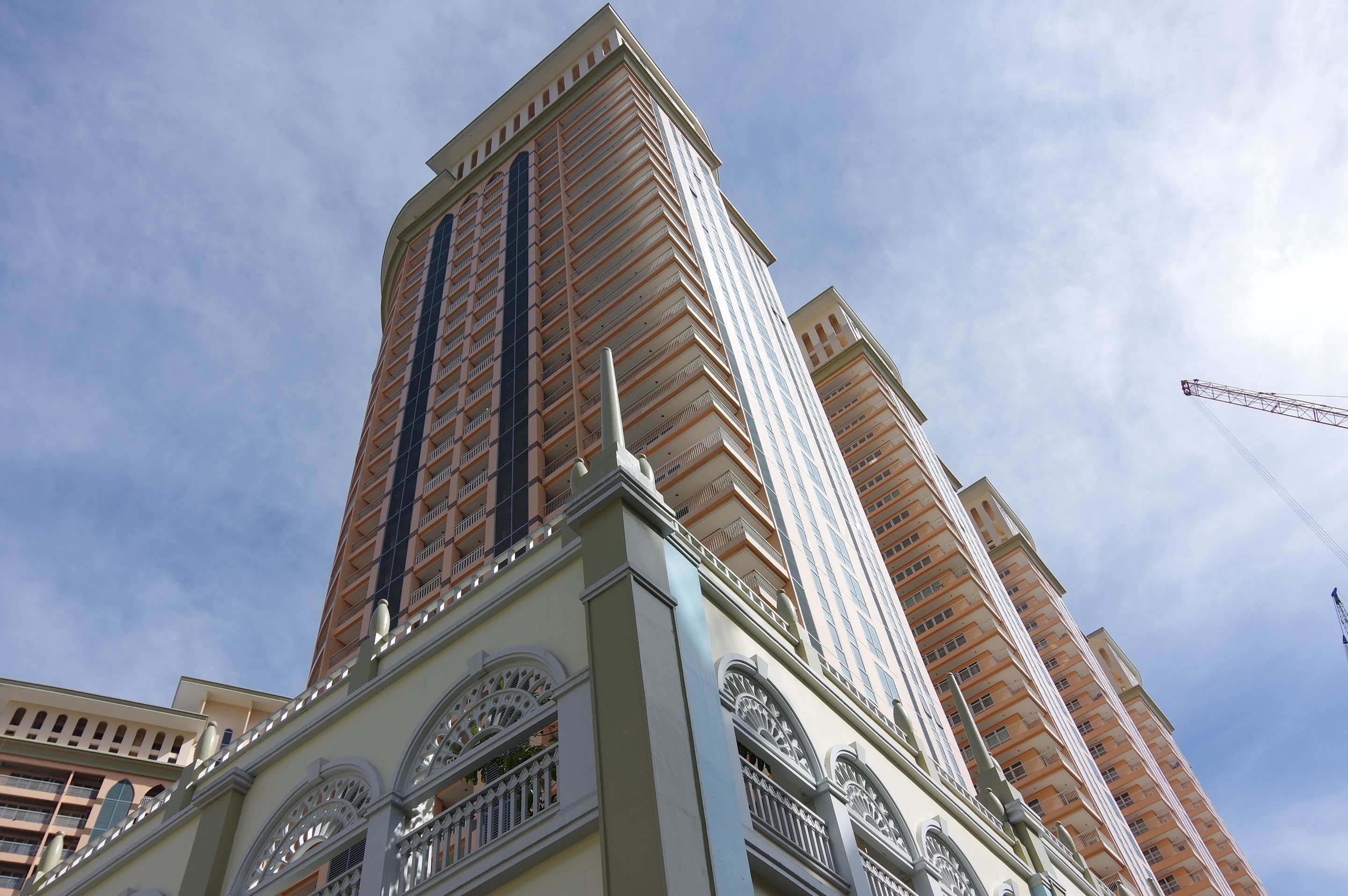 Um edifício alto com design arquitetônico moderno, com várias varandas e um elemento vertical marcante.