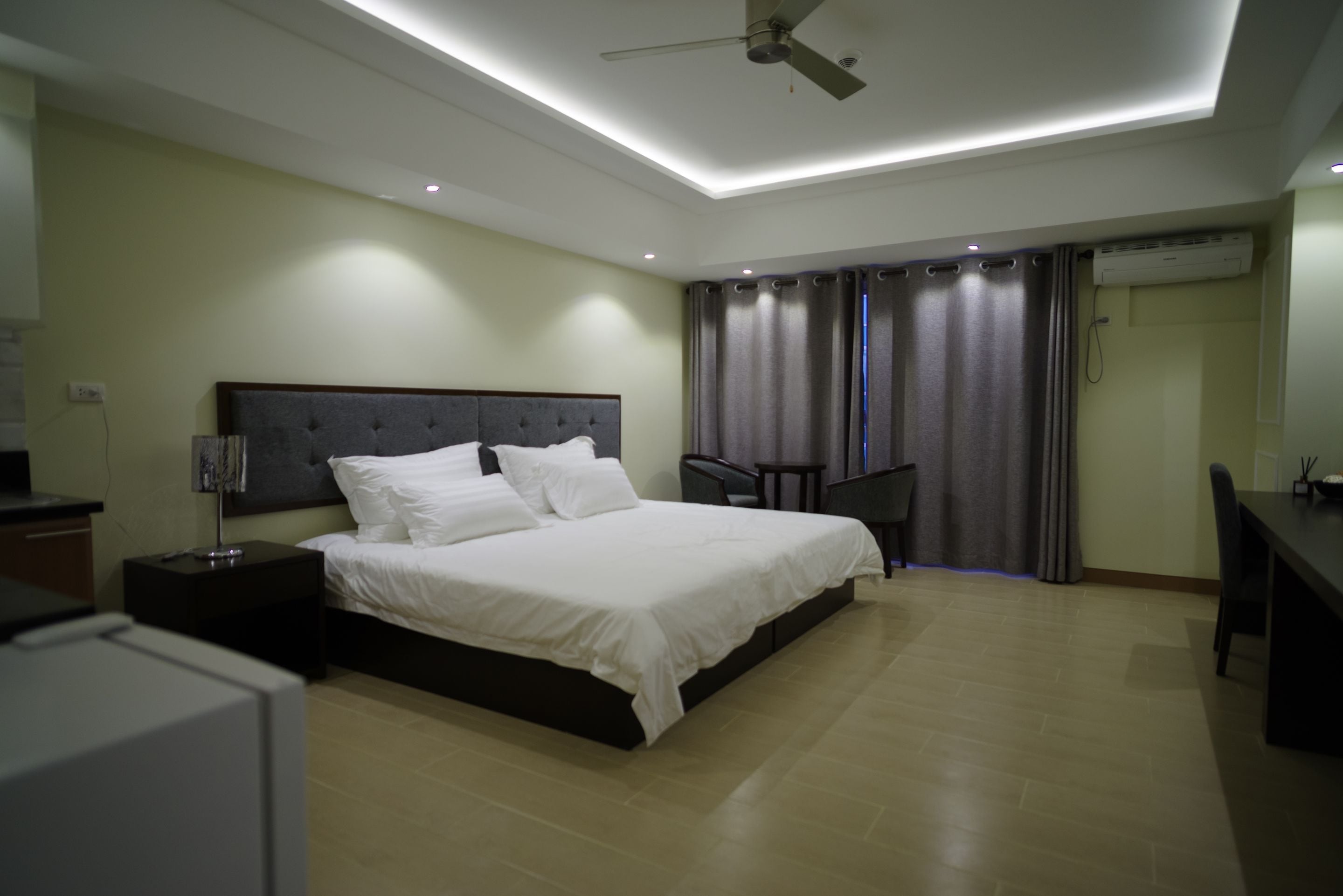A modern bedroom with a large bed, a desk, and a ceiling fan.
