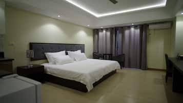 A modern bedroom with a large bed, a desk, and a ceiling fan.