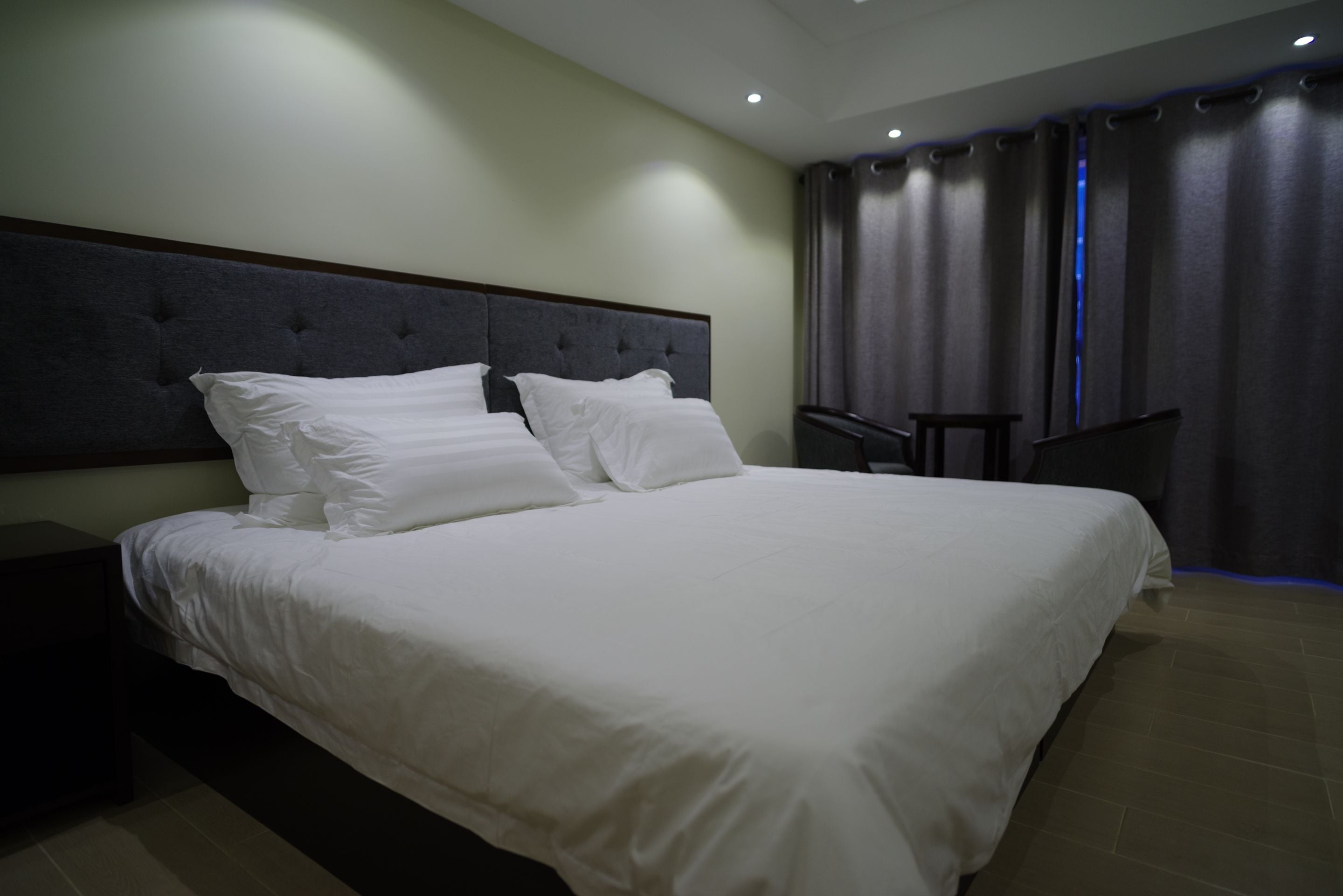 Una cama bien hecha con ropa blanca y un cabecero acolchado en una habitación de hotel moderna.