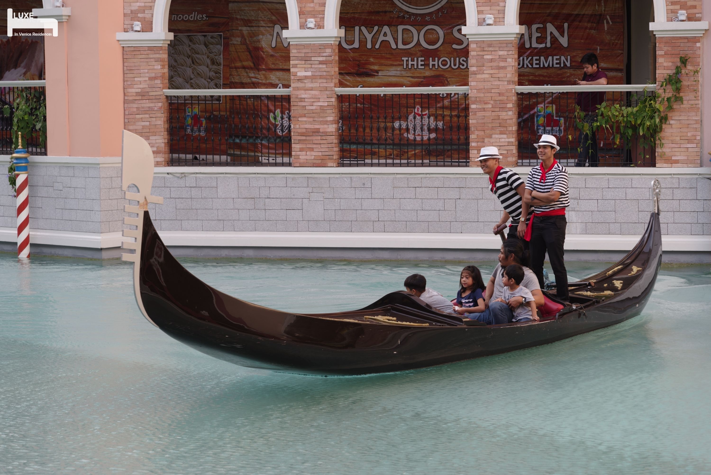 A gondola with passengers and a guide in a waterway.