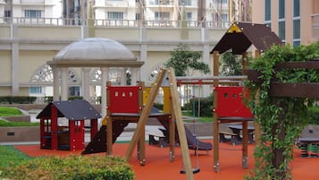 Children can play on the swing set, climbing structure, and in the playhouse amidst lush surroundings.