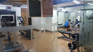 Un gimnasio con equipo de ejercicio, un reloj digital y carteles informativos.
