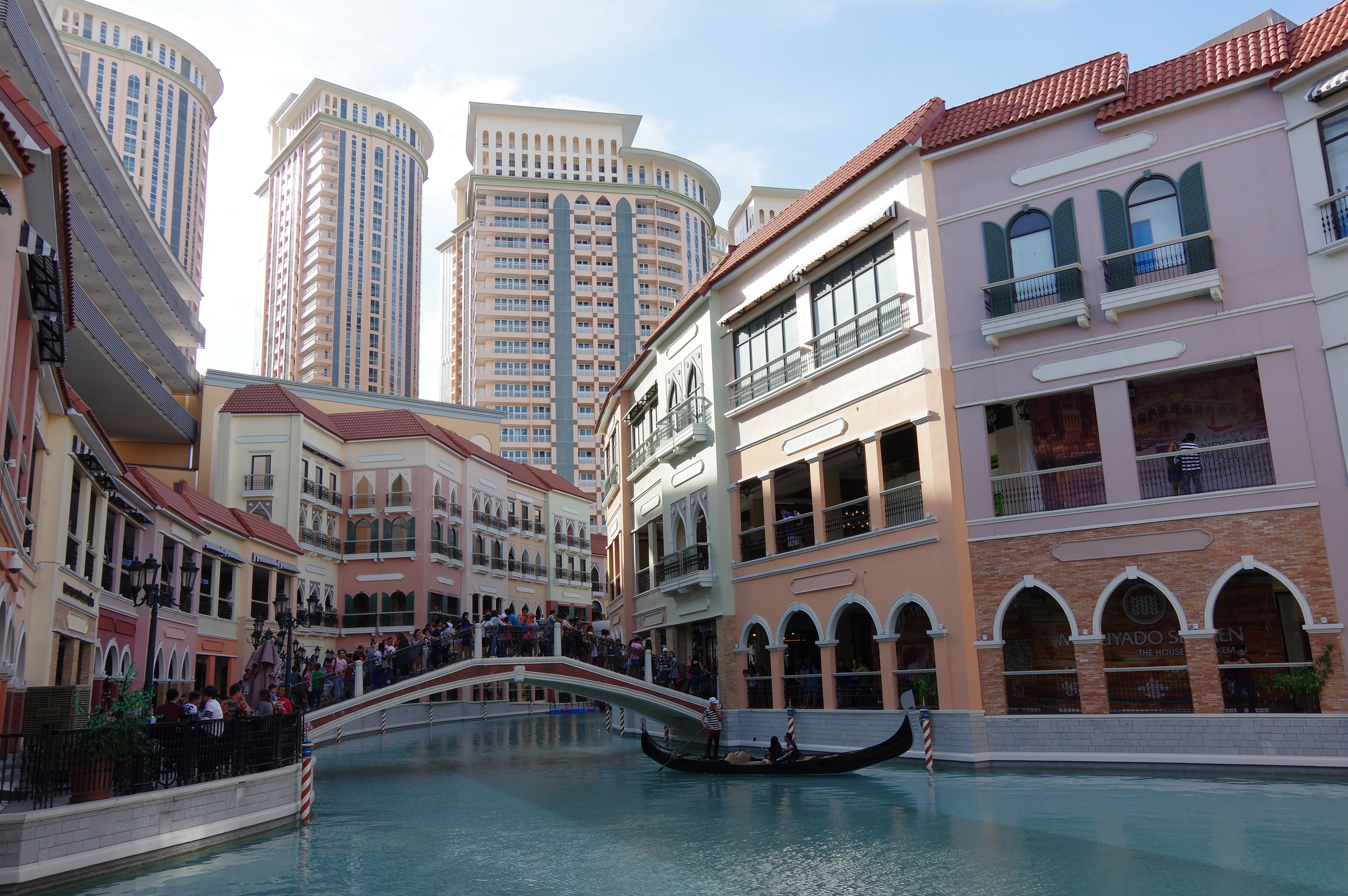 A canal with a gondola, surrounded by multi-story buildings with balconies and arched windows.