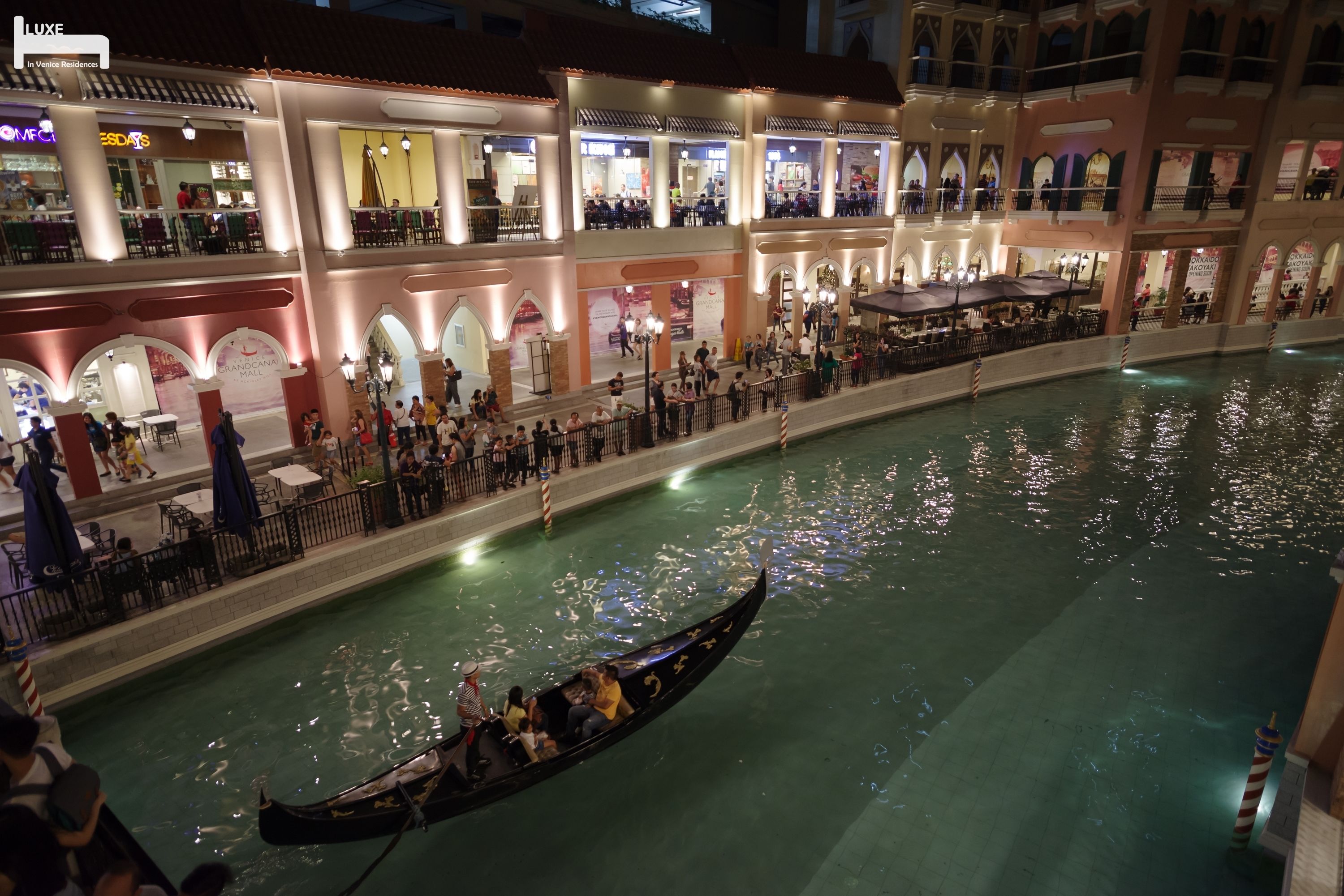 A gondola ride in a waterway within a hotel atrium, surrounded by dining areas and shops.