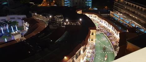 A high-rise hotel with a curved building structure, a central courtyard with a water feature, and a view of the cityscape at night.