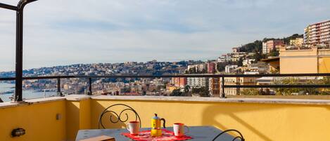 A balcony with a table, chairs, and a view of a cityscape.