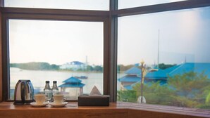 Vista desde una ventana con repisa de madera, una tetera, dos tazas y una caja de pañuelos.