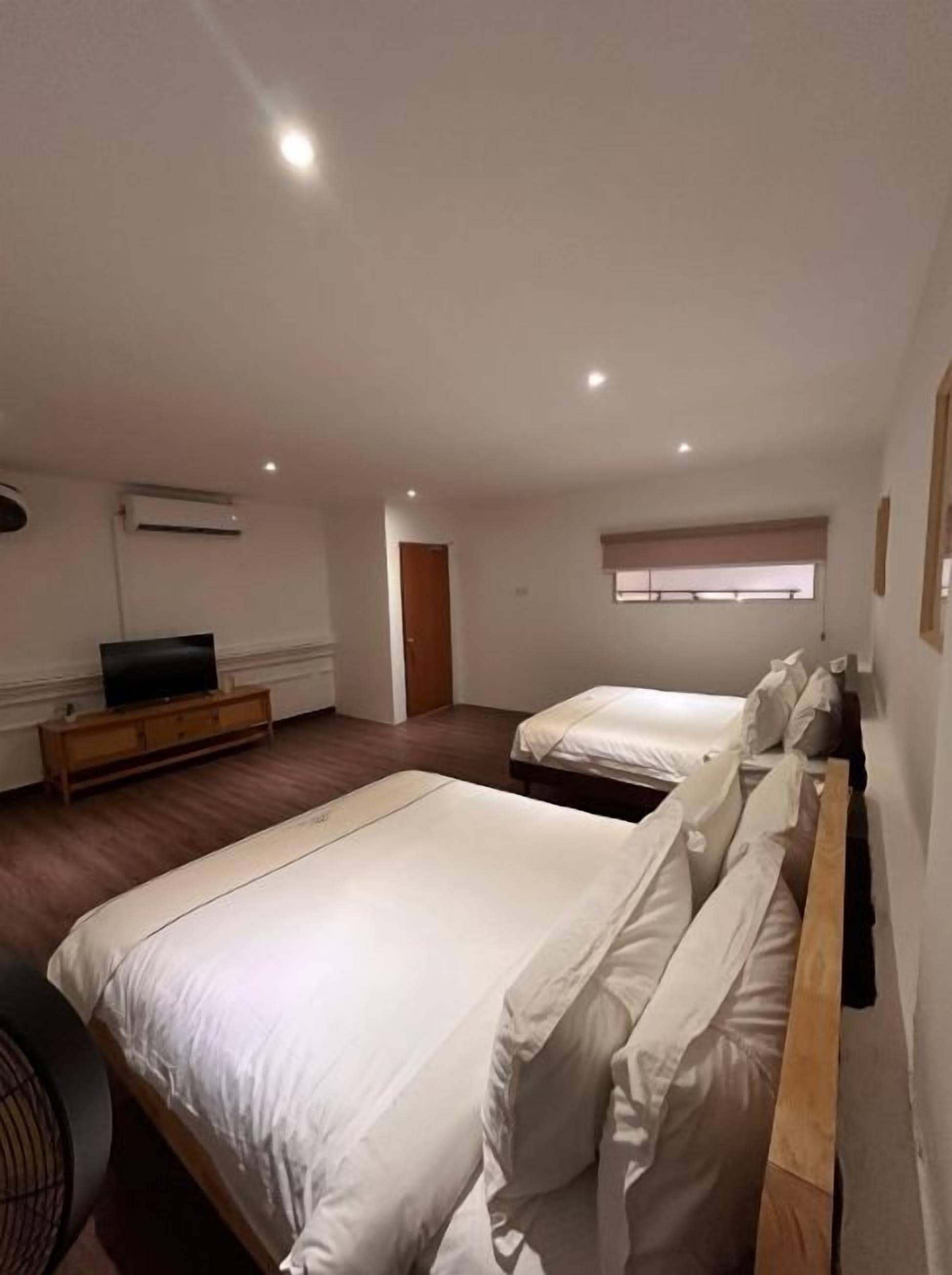 A hotel room with two beds, a television, and a window with blinds.