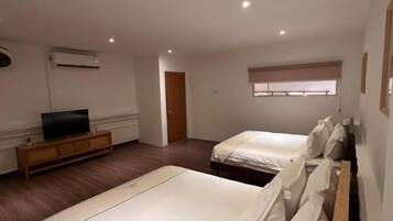 A hotel room with two beds, a television, and a window with blinds.