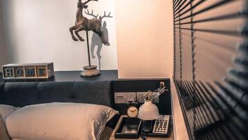 A bedroom with a bed, bedside table, lamp, clock, and a decorative deer sculpture.