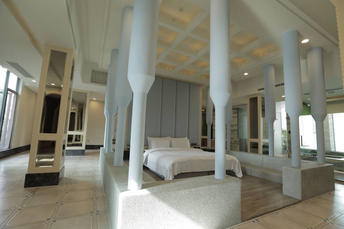 Une chambre d’hôtel moderne dotée d’un grand lit, d’un coin salon et offrant une vue sur l’extérieur.