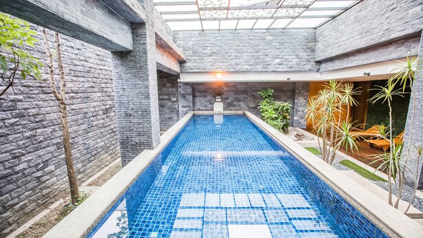 An indoor swimming pool with blue tiles, surrounded by stone walls and plants. - OHYA Chain Boutique Motel-Taoyuan  (Taoyuan City)