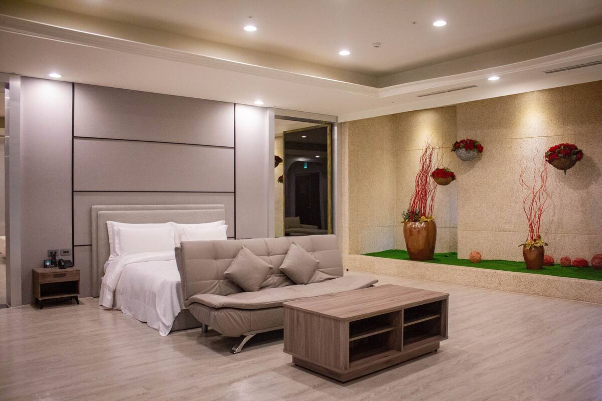 Une chambre moderne comprenant un lit, un canapé, une table de chevet et un présentoir à plantes fixé au mur.